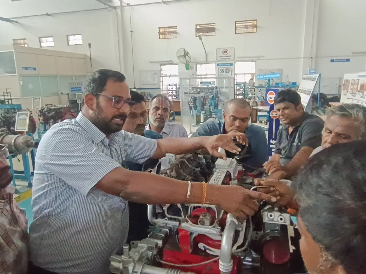 A trainer walking a group through engine components on a bench