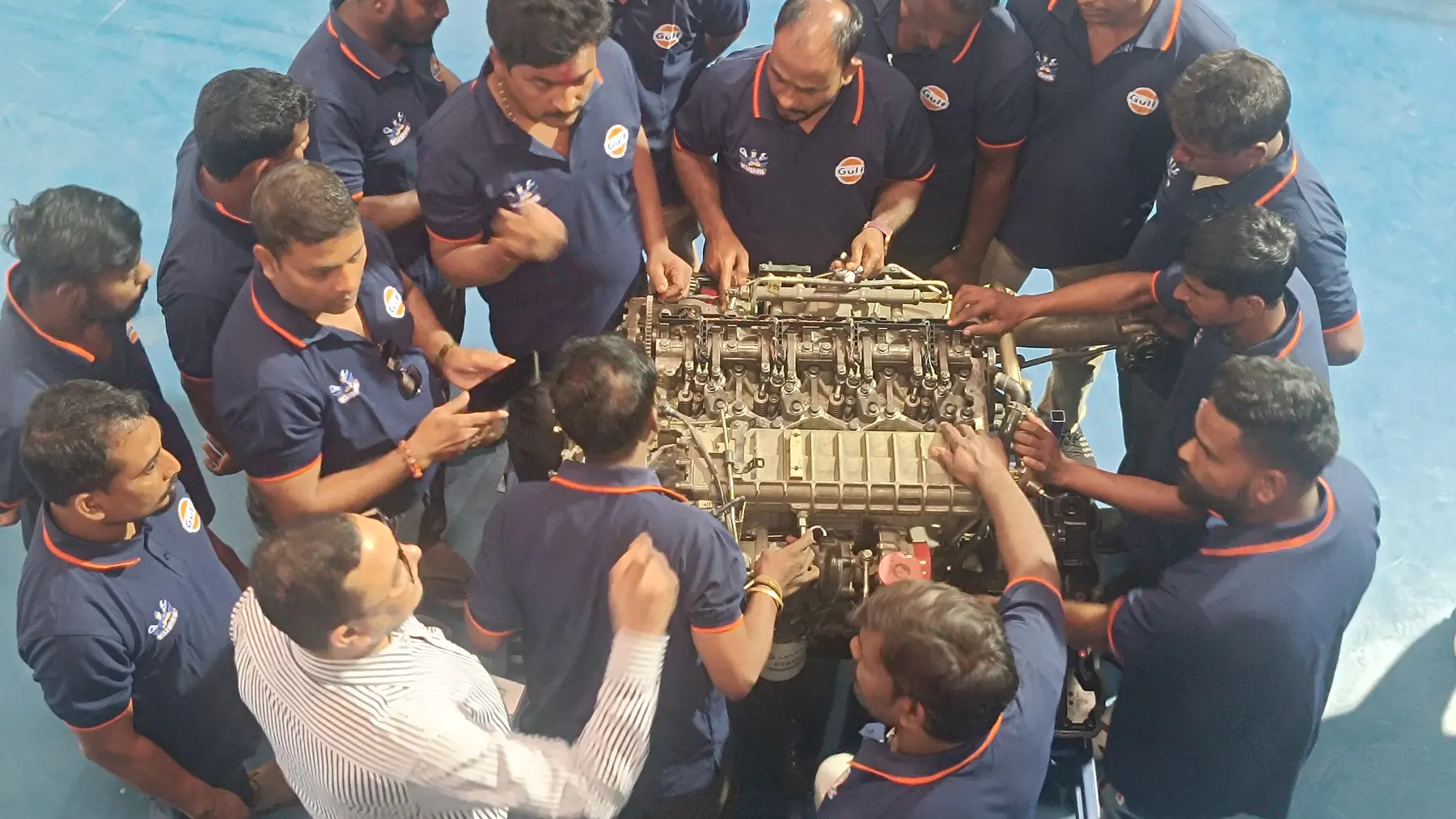 A cohort of technicians gathered around a heavy-vehicle engine on a training stand